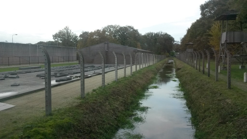 Je ziet op de foto de gracht die door gevangenen is gegraven. Rechts zie je de wachttoren, waar vooral Nederlanders in zaten die de kant van de Duitsers gekozen hadden.